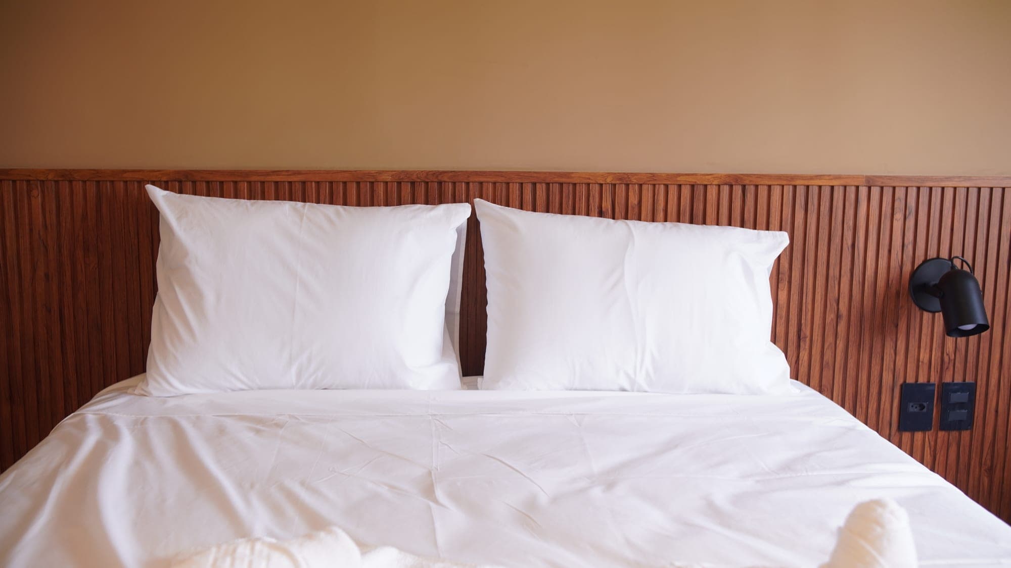 Cama do Liz Hotel com travesseiros macios e iluminação aconchegante