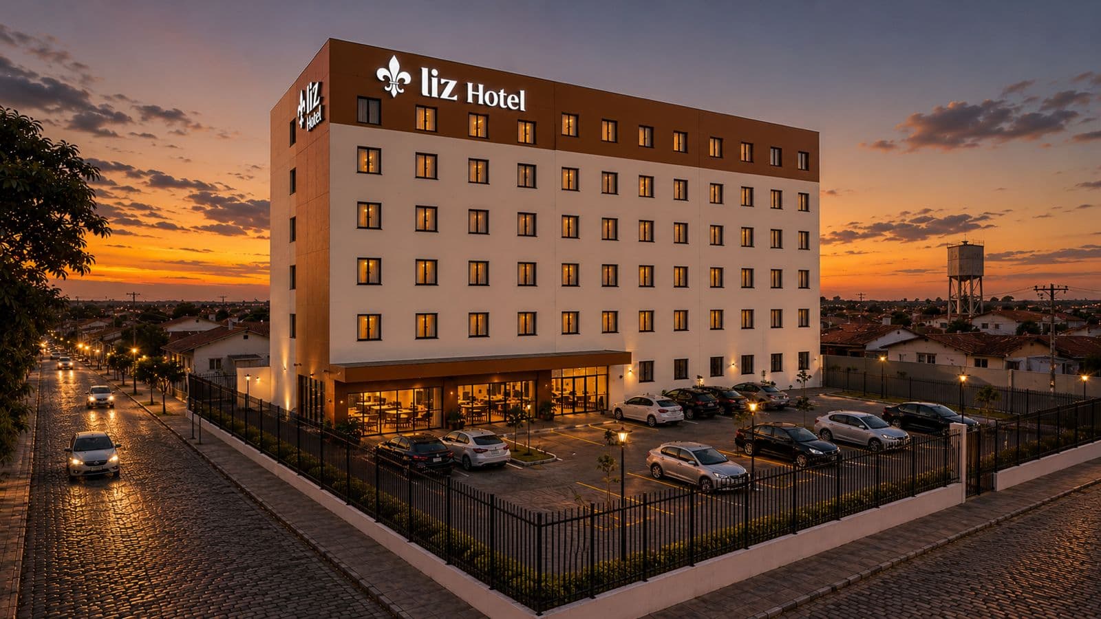 Fachada do Liz Hotel ao entardecer com iluminação e pôr do sol